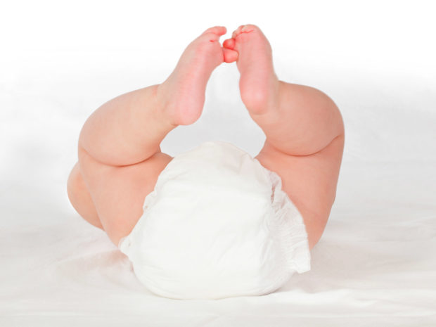 bambino con pannolino coricato con le gambe alzate