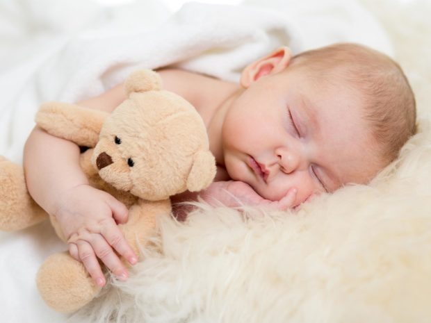 neonato dorme sereno abbracciato al suo orsacchiotto di peluche