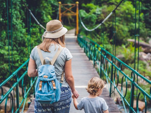 mamma e figlio passeggiano su un ponte in mezzo alla natura