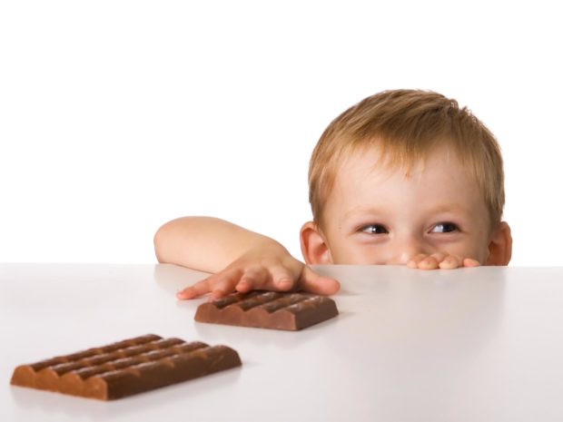 bambino prova a prendere le barrette di cioccolato da un tavolo