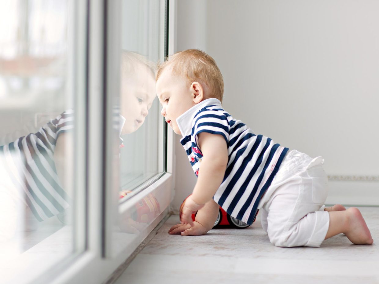 bambino gattona guardando fuori dalla porta a vetri