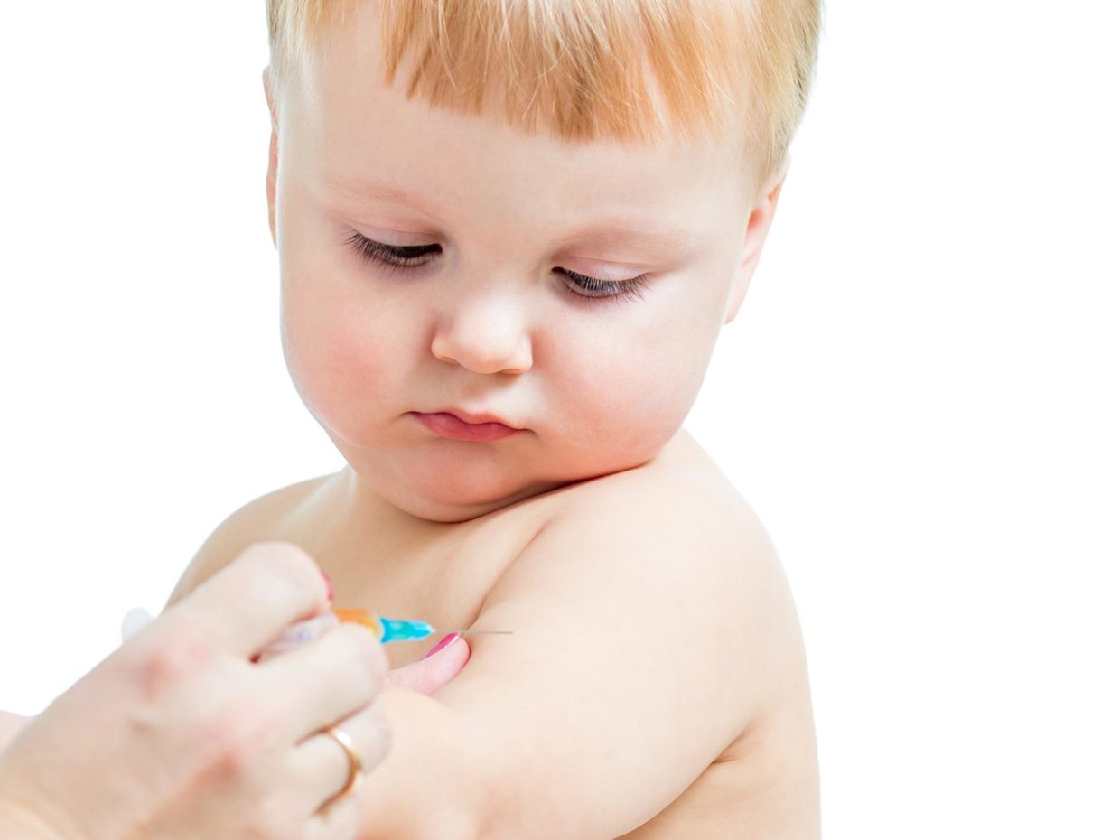 neonato guarda mentre gli viene somministrato un vaccino tramite siringa