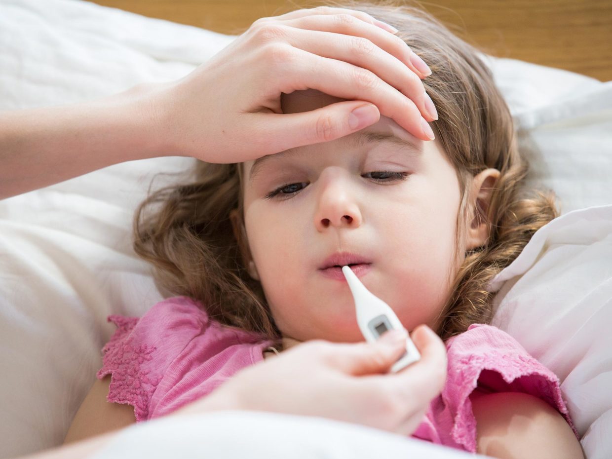 bambina a letto misura la febbre con il termometro