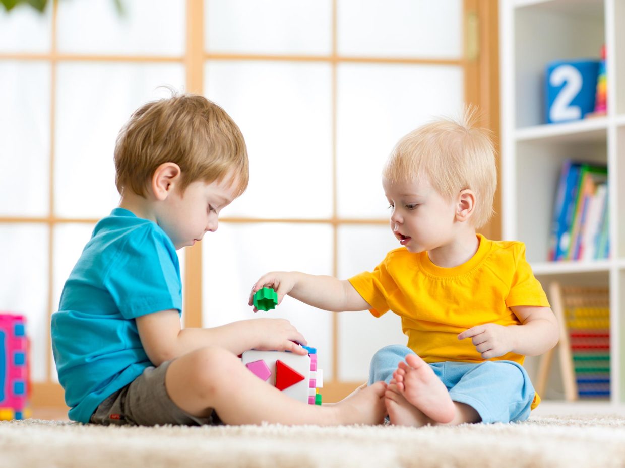 due bambini giocano con i mattoncini colorati sul pavimento di casa