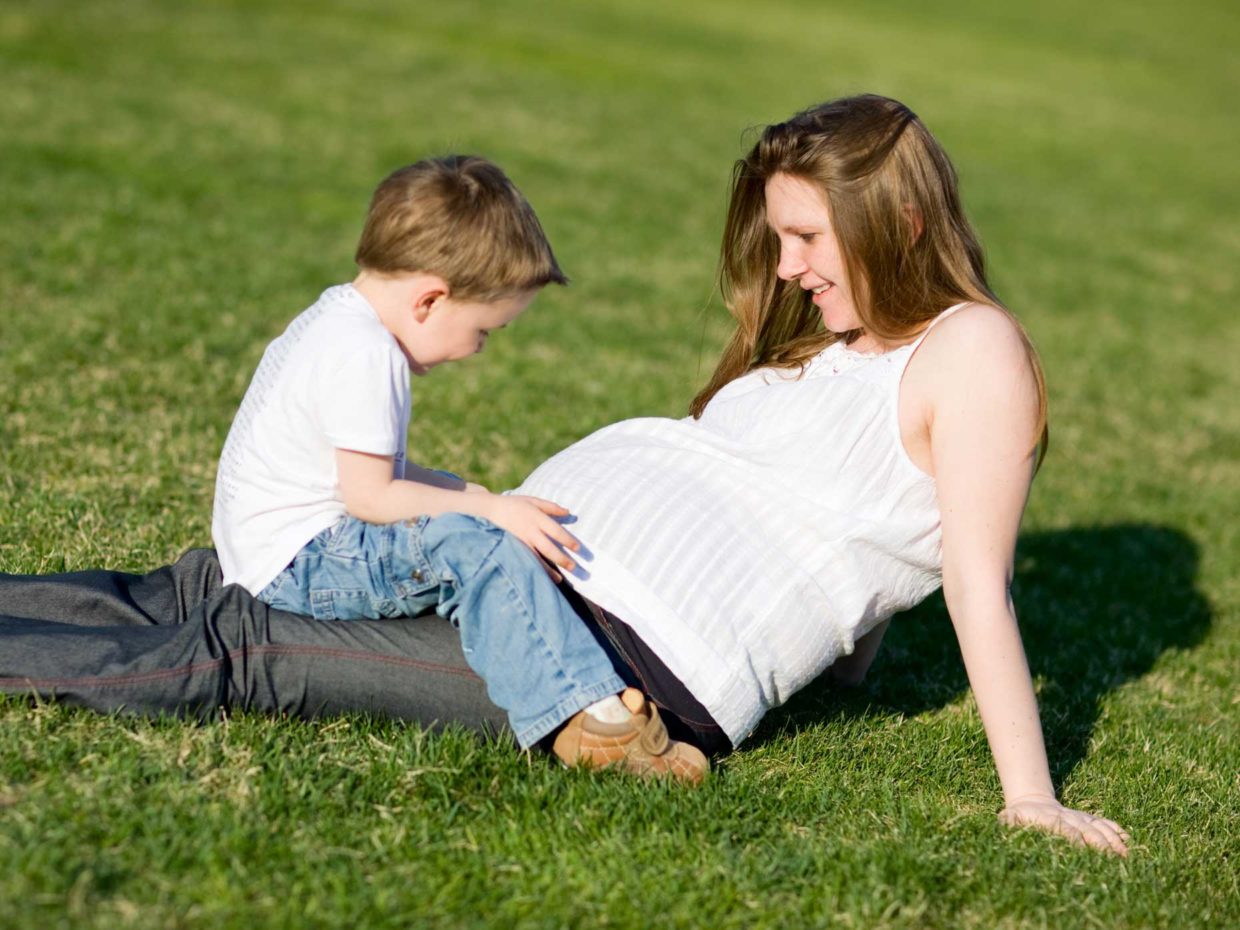 donna incinta distesa nel prato con suo figlio
