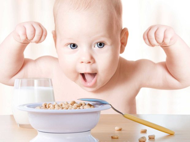 bambino esulta davanti una ciotola di cereali e un bicchiere di latte