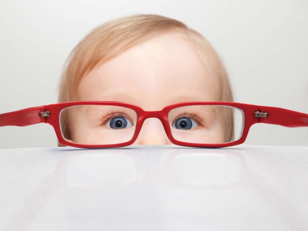 viso di bambino in primo piano con occhiali da vista rossi