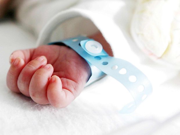 mano di neonato appena nato in ospedale con al polso il braccialetto di riconoscimento